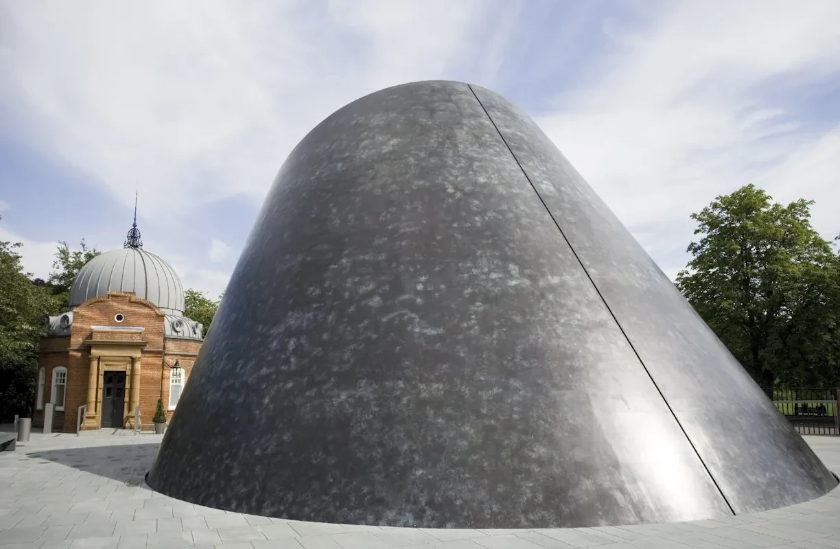 External view of the grey planetarium dome against a cloudy sky.