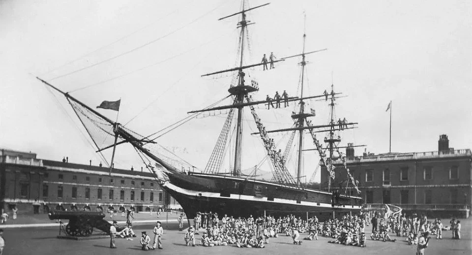 A black and white photograph showing people in Navy uniform on and around the drydocked Cutty Sark.