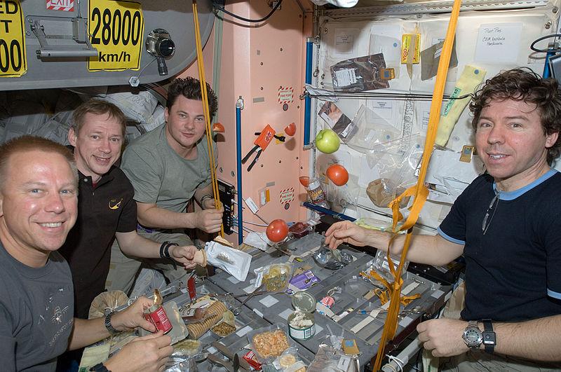 Crew members share a meal at a galley in the Unity node of the International Space Station