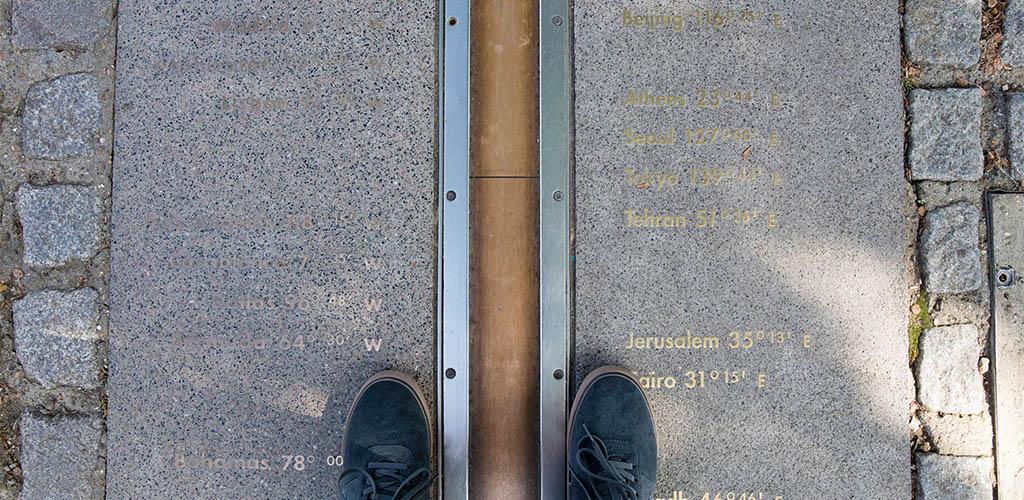 A top-down photo of feet on the Prime Meridian line.