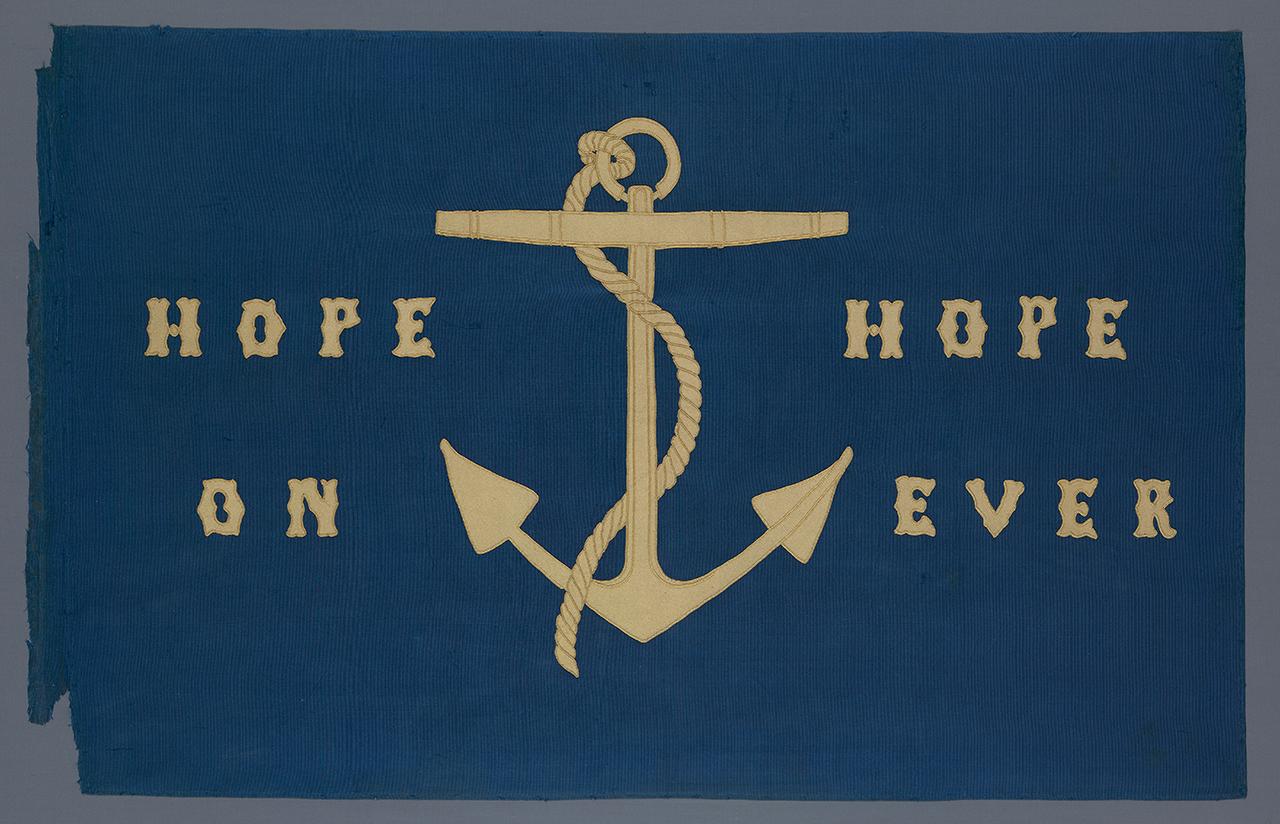 A blue flag with the motto 'HOPE ON HOPE EVER' embroidered in yellow letters around an anchor