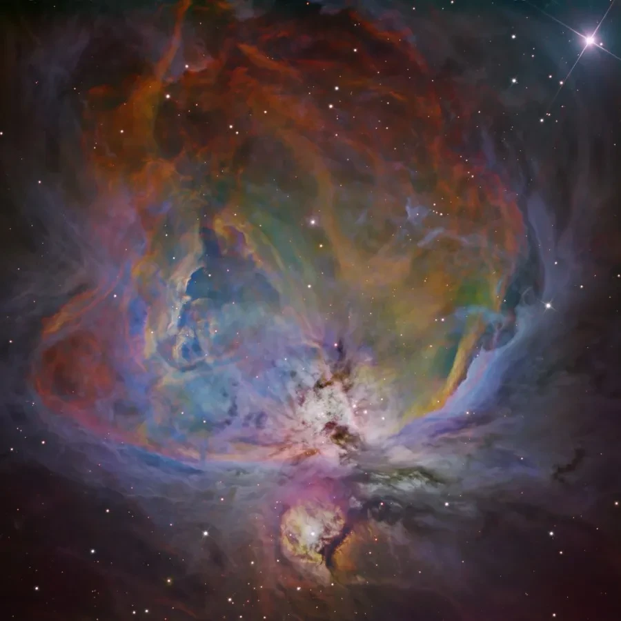 A colourfully-filtered astronomy photograph of a nebula in the dark sky.