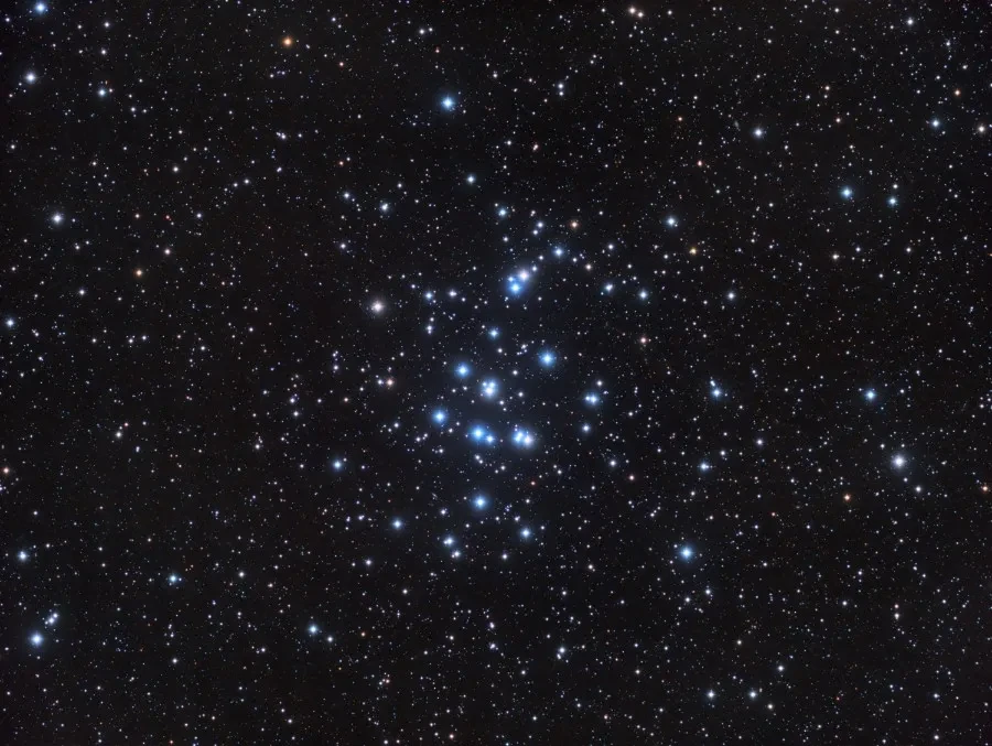 A cluster of bright stars in a black, starry sky.