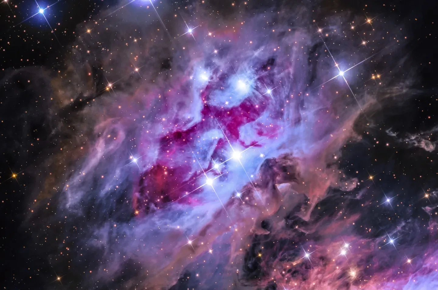 A colourfully-filtered astronomy photograph of a nebula in the dark sky.
