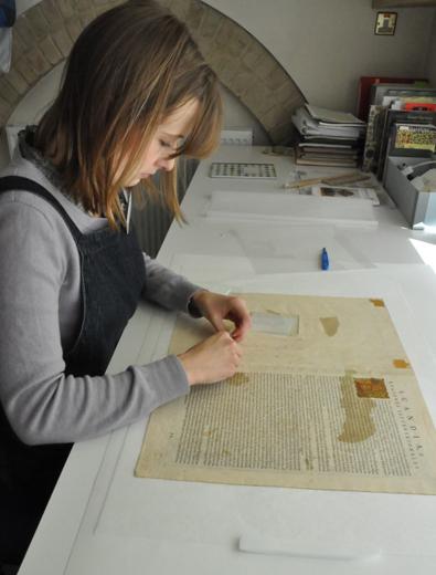 Applying the remoistenable tissue to the verso of one of the maps
