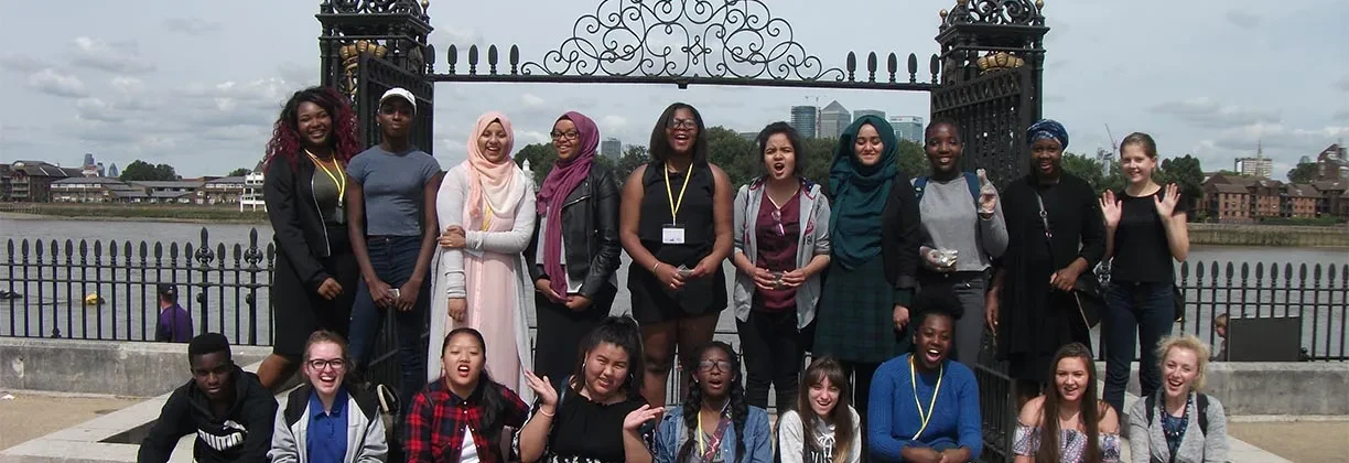 A group of young people pose in front of the Thames.