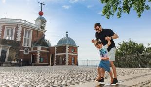 A father and son play on the Prime Meridian Line outside the historic Flamsteed House building of the Royal Observatory
