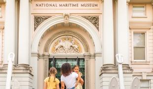 A family walk into the main entrance of the National Maritime Museum in Greenwich