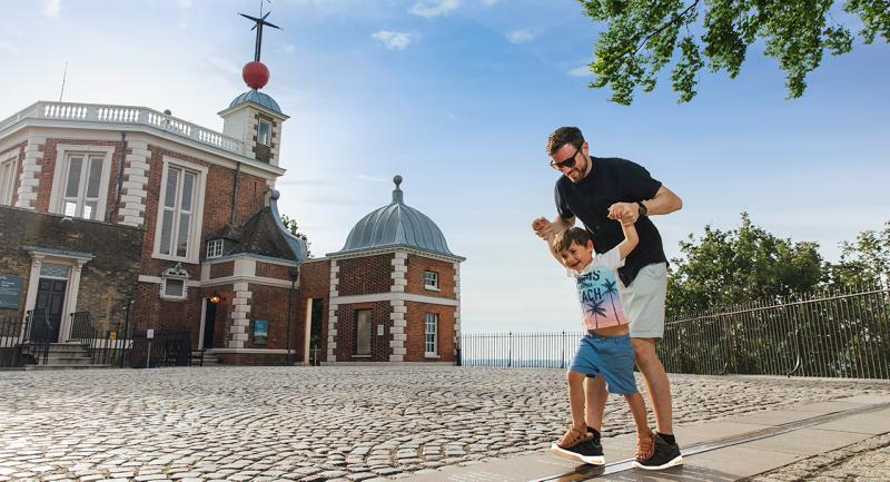 A father and son play on the Prime Meridian Line outside the historic Flamsteed House building of the Royal Observatory