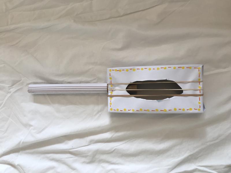 banjo made from a cardboard and a cardboard tube and rubber bands covered in white paper