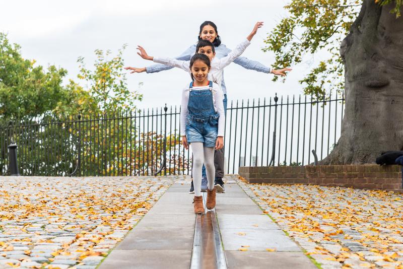 A family walks along the Prime Meridian Line at the Royal Observatory in Greenwich