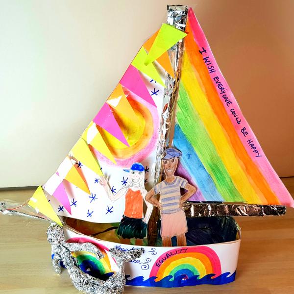 crafted boat with with rainbow sails, bunting, rainbows on the hull and two figures inside