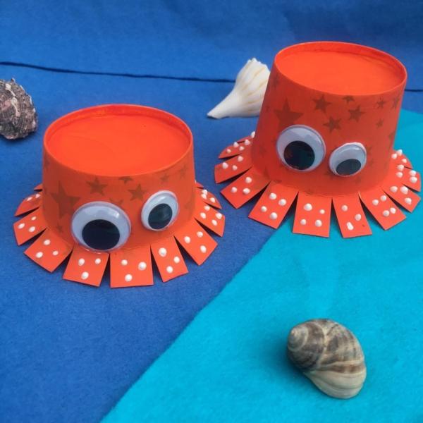 orange octopus craft on blue paper with shells