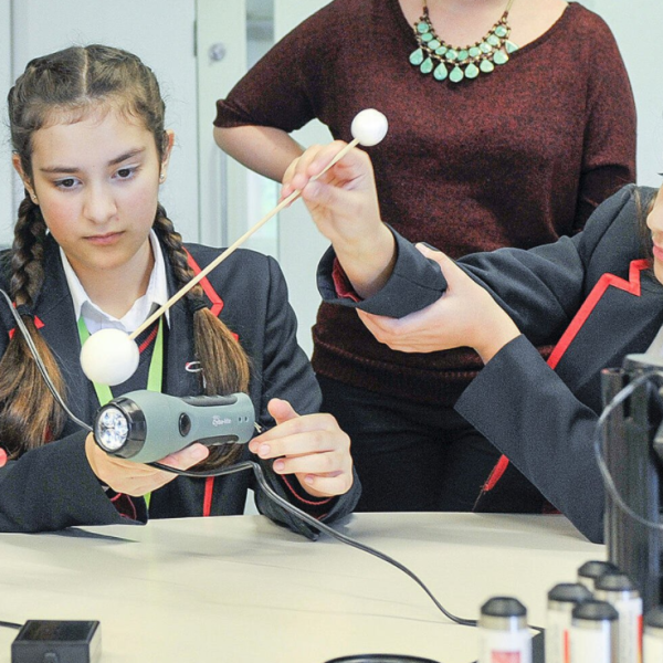 Two students using a stick with a planet ball, light sensor and datalogger to demonstrate exoplanet detection through analysing light curves