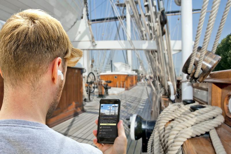 A man follows an audio guide tour of Cutty Sark on his phone