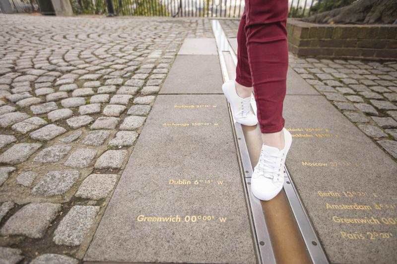 A close up of a woman's feet as she walks along the Prime Meridian Line in Greenwich, the line marking Greenwich Mean Time