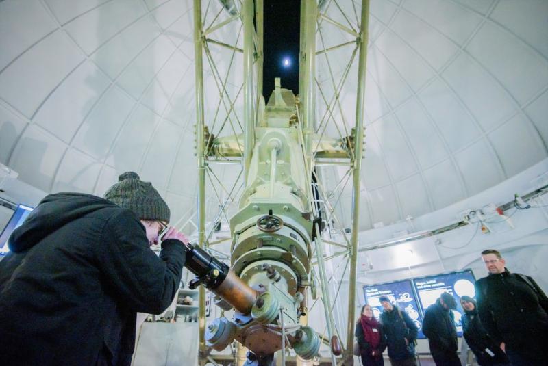 A woman looks through an historic telescope at the Royal Observatory during an evening stargazing event