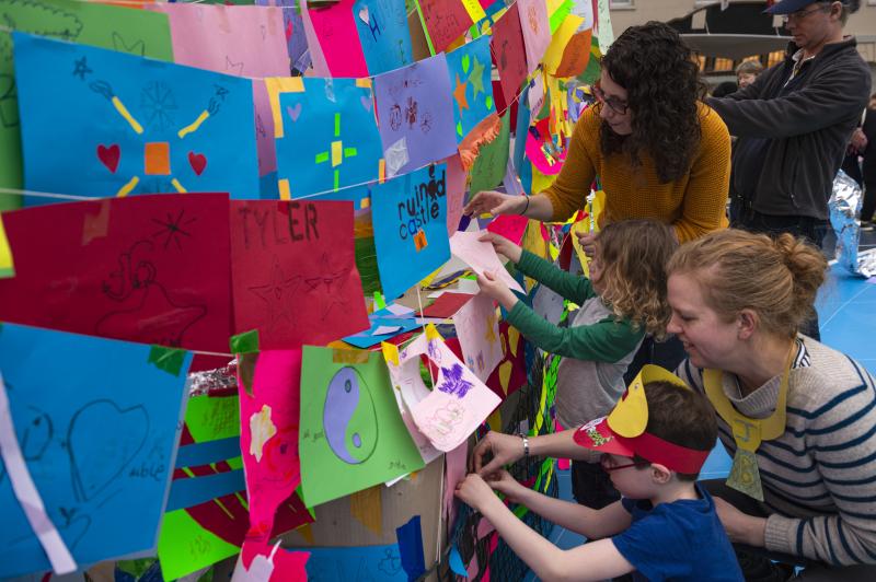 A family adding to a large collaborative art piece