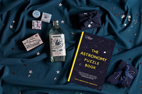 The Astronomy Puzzle Book, a bar of soap and some toiletries displayed on a rich blue background