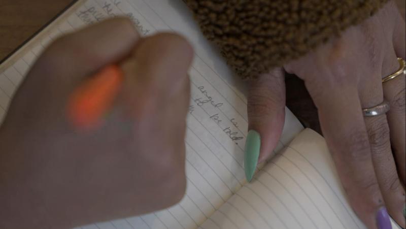 A hand writing a poem in a notebook