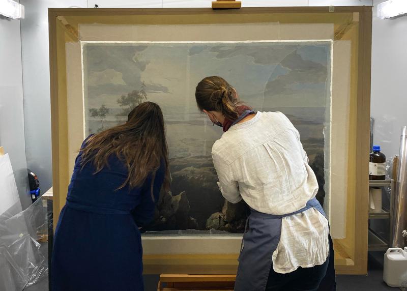 Two paintings conservators examine a painting