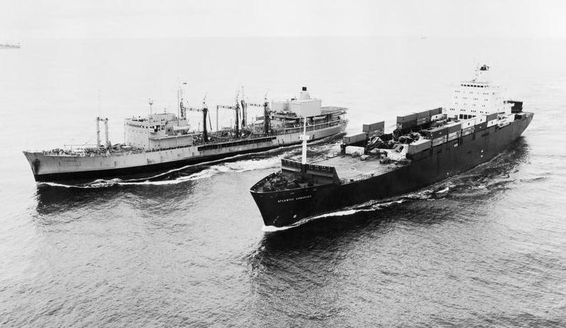Black and white photograph showing two ships at sea. One is refuelling the other