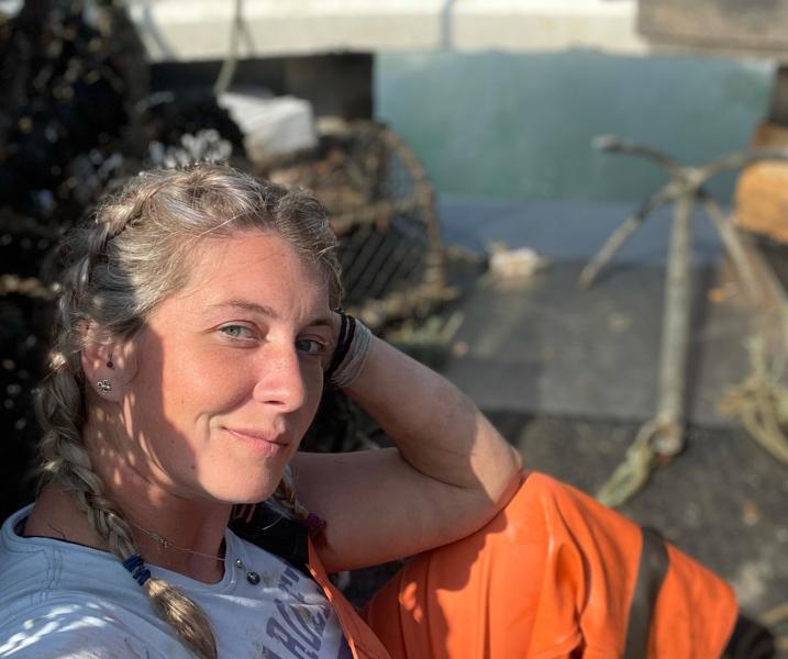 Ashley Mullenger wearing a boiler suit and sitting on a fishing boat