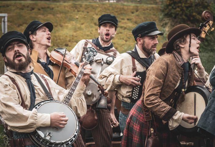 Image of group of people dressed as sailors and holding instruments singing