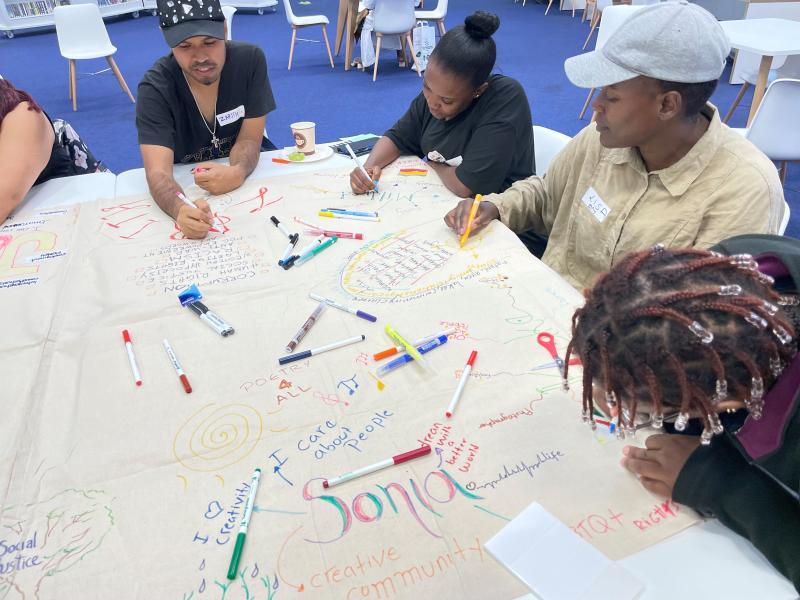 A group of people writing on canvas at a poetry workshop