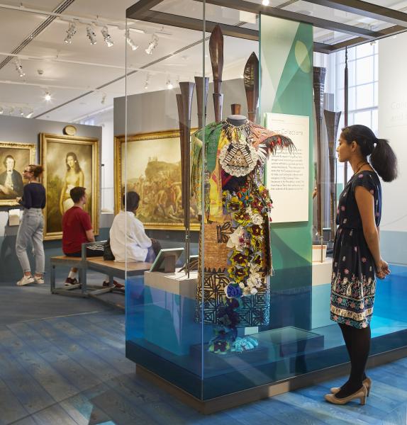 A woman looks at a dress displayed in a glass case inside the Pacific Encounters gallery of the National Maritime Museum