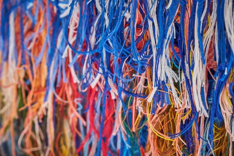 A close-up view of multiple colourful strands of cotton used to weave a tapestry