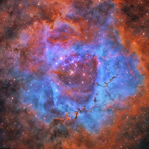 Rosette Nebula surrounded by blue, pink and orange hues