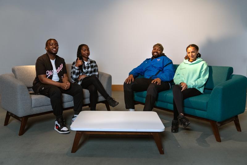 A group of people sit on a sofa in conversation