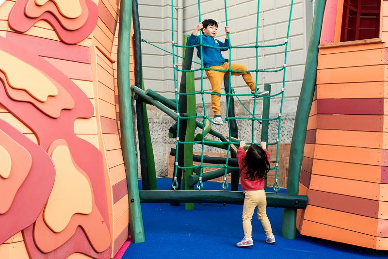 A boy climbs a cargo net in the National Maritime Museum's new playground, with his sister looking on from the ground