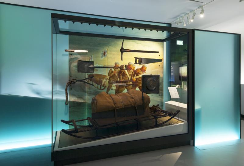 A display of historic polar exploration equipment and sledges in a glass case at the National Maritime Museum